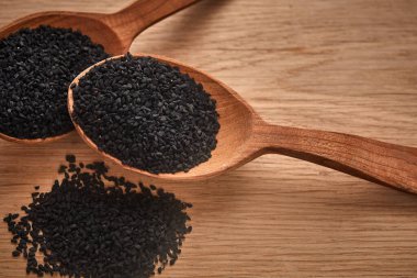 Siyah kimyon tohumları ve ahşap bir masanın üzerinde bir şişe yağ bulunan tahta bir kaşık. Sağlıklı, vejetaryen, organik gıda konsepti. Kapat.