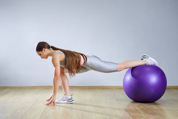 Young fit woman exercising in a gym. Sports girl is training cross fitness with a Pilates Balls.