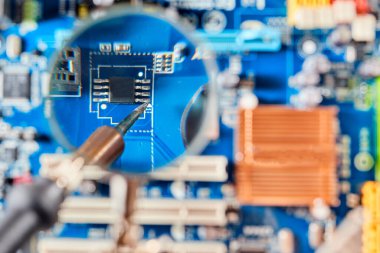 Elektronik levhayı büyüteçle lehimlemek. Bilgisayarın elektronik parçaları: ana kart, mikroçip. Yakın çekim.