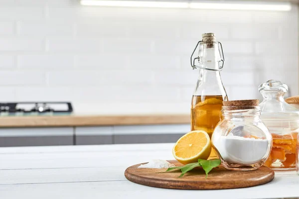 Eco-friendly natural cleaners: baking soda, soap, vinegar, salt, coffee, lemon and brush on a wooden table. Zero waste concept. Kitchen background.