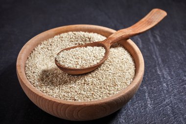 Susam tohumları ve karanlık bir masada kaseli tahta bir kaşık. Sağlıklı yiyecek ve içecek konsepti. Üst Manzara. Kapat.