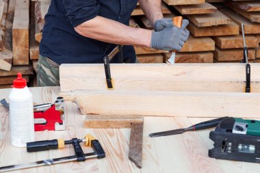 Kesiciyle çalışan marangoz elleri. Ahşap arka planda uçakla çalışan bir adam. Marangozluk işine katılan biri..