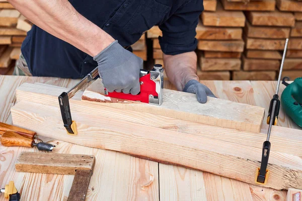 Male carpenter hands using sandpaper on a plank of wood for handmade furniture. Close up. Wooden table.