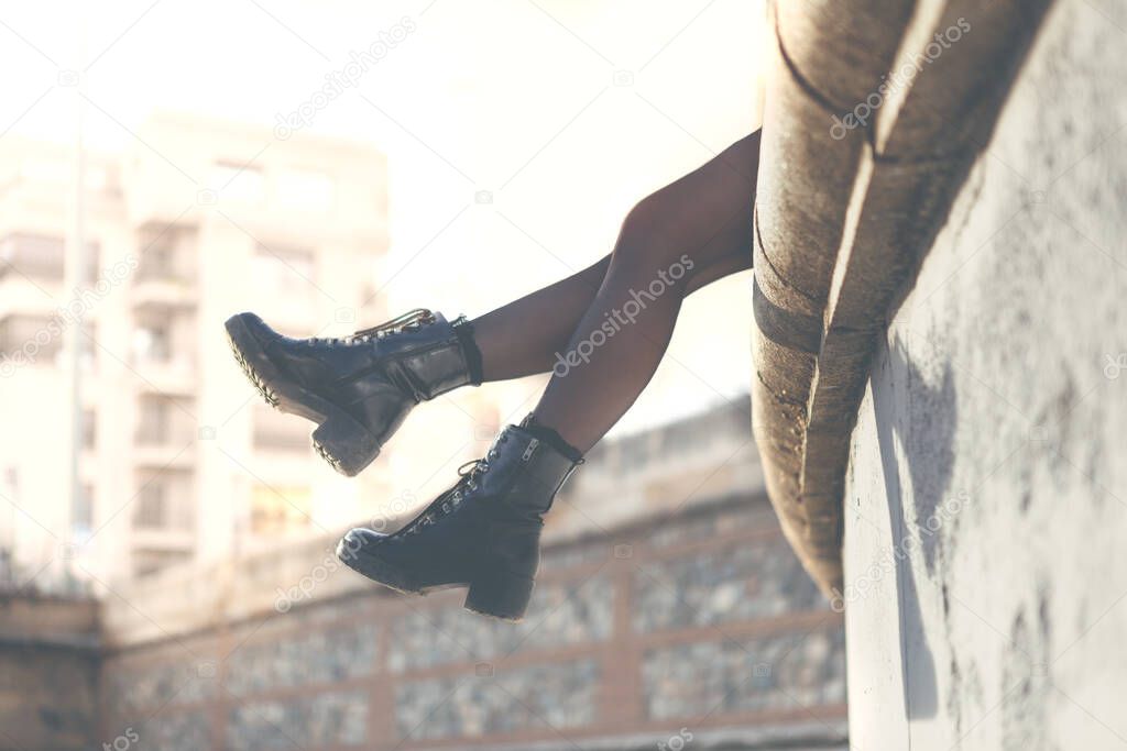 Legs with boots of a young urban girl sitting, raised in the air