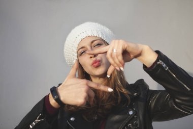 Güzel gülüşü olan, dudaklarını elleriyle öpen bir kız.