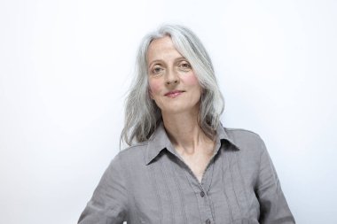 Stüdyoda beyaz saçlı ve beyaz arka planda olgun bir kadının portresi.