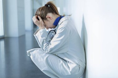 Genç bayan doktor üzgün ya da yorgun bir tavırla hastane koridorunda oturuyor.