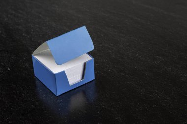 Koyu arkaplan üzerine beyaz not kağıtlarının olduğu mavi kutu. ofis notları..