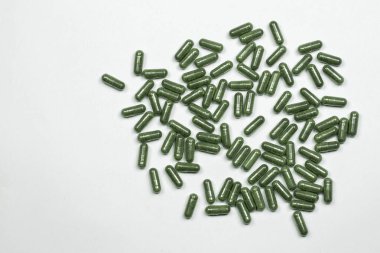 Yeşil bitkisel kapsüller, beyaz arka planda bitkilerden alınan haplar, haplar...