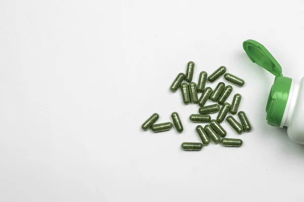 Зелені трав'яні капсули таблетки з трав на білому тлі, таблетки вид зверху .. — стокове фото