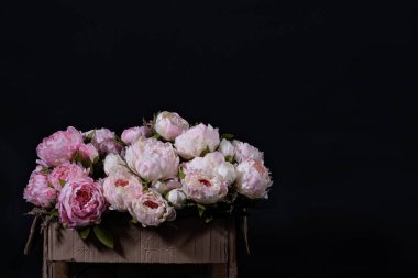 Siyah arka planda karton kutuda pembe ve beyaz şakayık demeti