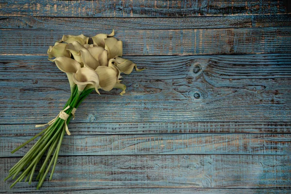 Ahşap mavi arka planda sarı calla çiçekleri.