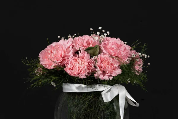 Pink carnation flowers bucket in glass vase on black background