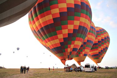Gündoğumunda turistlerle kalkış için sıcak hava balonları hazırlanıyor.