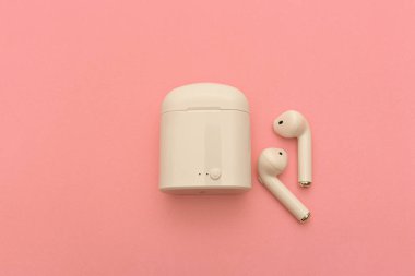 Hava kapsülleri. Kablosuz kulaklıklar ve pembe arka planda kablosuz şarj cihazı. Boşluğu Kopyala