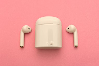 Kablosuz kulaklıklar ve pembe arka planda kablosuz şarj cihazı. Boşluğu Kopyala.