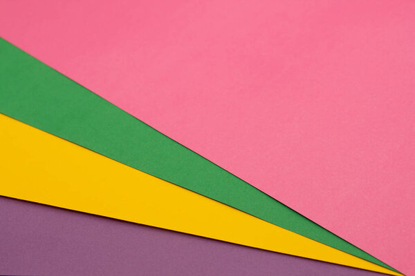 Multi colored paper background of pink, green, yellow and purple