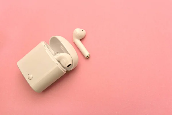 wireless headphones and wireless charging Case on pink background. Copy Space