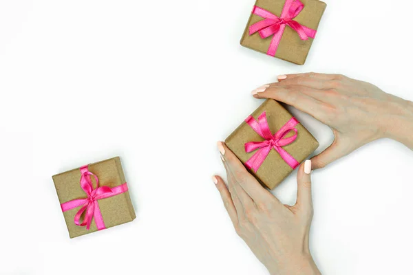 礼物盒的平铺，白色背景上有女性手和粉色缎带。复制空间 — 图库照片
