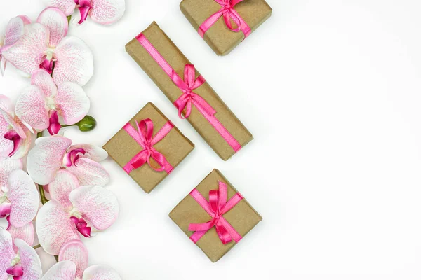 Flachlagen von Geschenkboxen mit rosa Schleife mit Orchideenblüten auf weißem Hintergrund. Frühlingskonzept. Kopierraum — Stockfoto