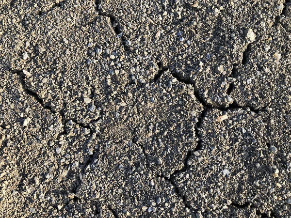 Тріснутий сухий ґрунтовий бруд, висушений під сонячною дорогою . — стокове фото