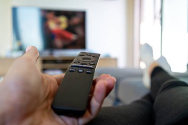 Televizyon izlemek, büyük televizyonun önünde uzaktan kumandayı tutmak.