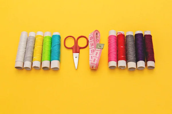 Rosca, agulhas, tesoura e medidor no fundo amarelo. alfaiataria. kit de costura multi-colorido . — Fotografia de Stock