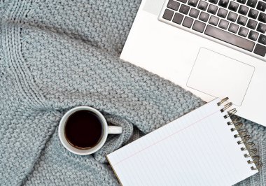 Sıcak kahve, dizüstü bilgisayar ve aksesuar yazan rahat bir çalışma yeri. Evden çalışıyorum. Yazmak. Soğuk havada sıcak konsept.