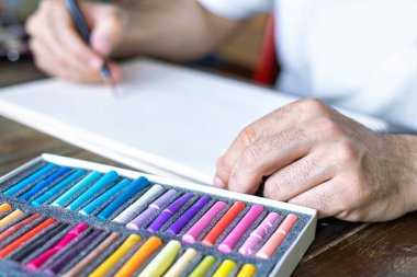 Pastel pastel boya kalemi ile beyaz bir kağıt ve pastel tebeşirle boyanmış bir kutu.