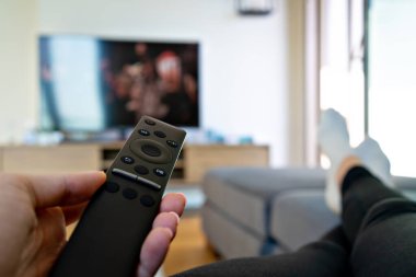 Televizyon izlemek, büyük televizyonun önünde uzaktan kumandayı tutmak..