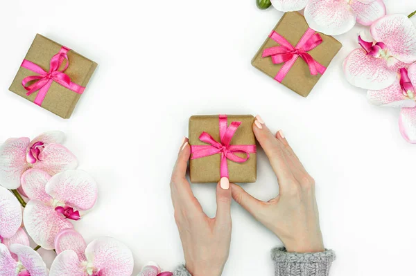 送礼盒的平铺 用女性的手和粉色带兰花白色背景顶部的观点 礼物或礼物春天的概念 复制空间 — 图库照片
