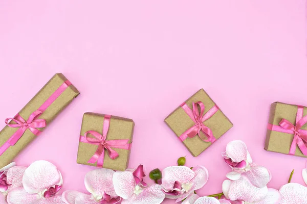 礼物盒的平铺，盒子上有粉色缎带，兰花背景是粉红色的。复制空间 — 图库照片