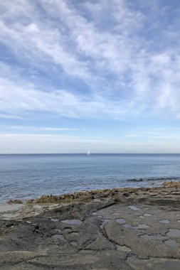 Taş kesilmiş deniz kenarı. Denize yakın, mavi gökyüzü taşlaşmış kumsalda