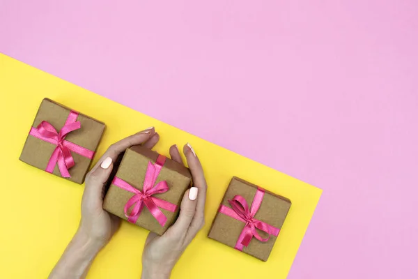 礼物盒的平铺 有粉红缎带 粉红黄色背景 女性手 顶层空间 — 图库照片