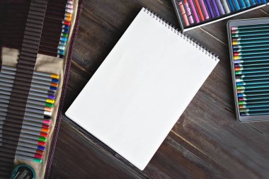 Resim atölyesi, kalemler, fırçalar, suluboya boyalar, kanva kağıtları ve pastel boya tebeşirleri. Tahta masanın üzerinde yatıyordu..