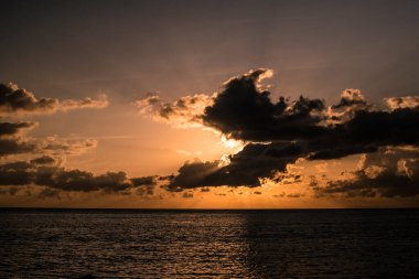 Güneşin önündeki büyük bulutlarla okyanusun üzerinde gün batımı