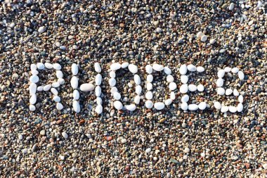 Rodos bir çakıl taşı plajında taşlara yazılır..