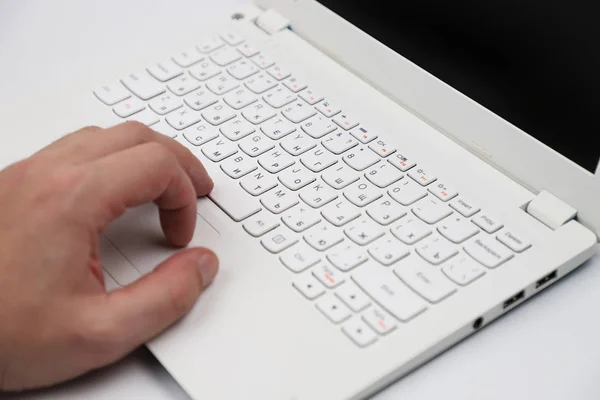 Laptop white on a white background, hand on the keyboard.