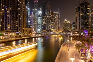 Dubai Marina 'da gece görüşü, gökdelenler, ışıklar, gezinti güvertesi, Boğaz. Yavaş deklanşör hızında çekilen.