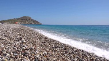 Afandou plajı, Akdeniz kıyıları, çakıllı plaj, dalgalar, arka plandaki uçurum, Rodos adası Yunanistan.