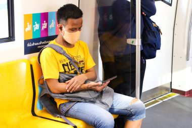 Bangkok metrosu. Maskeli bir adam arabanın içindeki telefona bakıyor. Tayland Bangkok Mart 2020