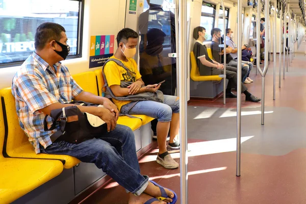 Bangkok metrosundaki tıbbi maskeli insanlar BTS Skytrain arabasının içinde. Tayland Bangkok Mart 2020