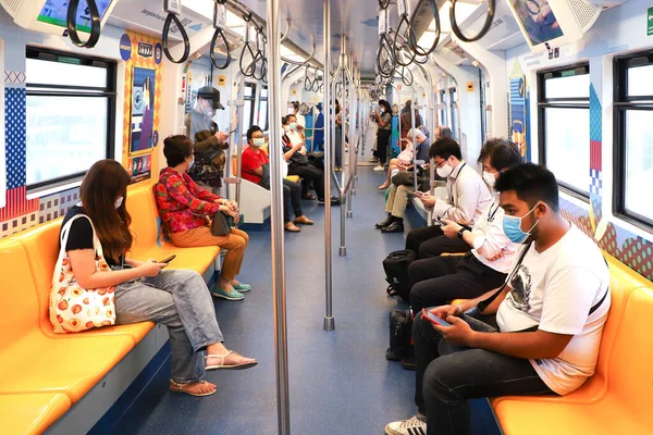 Bangkok metrosundaki tıbbi maskeli insanlar BTS Skytrain arabasının içinde. Tayland Bangkok Mart 2020