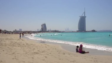 Jumeirah plajı, güneşli bir gün, insanlar rahatlar, yüzerler, arka plandaki Burj al Arab otelinde. Birleşik Arap Emirlikleri Dubai, Mart 2019