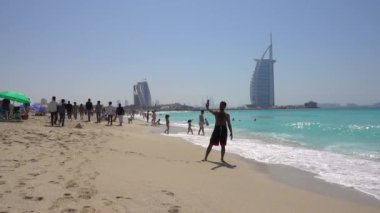Jumeirah plajı, güneşli bir gün, insanlar rahatlar, yüzerler, arka plandaki Burj al Arab otelinde. Birleşik Arap Emirlikleri Dubai, Mart 2019