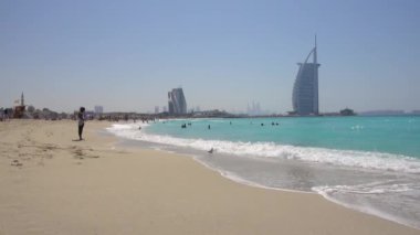 Jumeirah plajı, güneşli bir gün, insanlar rahatlar, yüzerler, arka plandaki Burj al Arab otelinde. Birleşik Arap Emirlikleri Dubai, Mart 2019