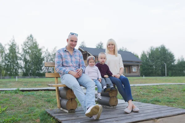 Família feliz de dois pais e filhos, um meninos, menina, sentados juntos fora — Fotografia de Stock
