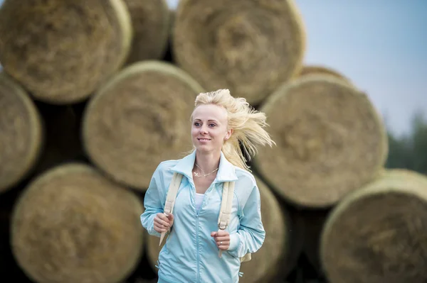 A garota romântica correndo ao ar livre contra a pilha de feno — Fotografia de Stock