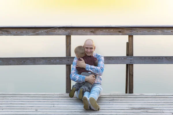 Vater und kleiner Sohn sitzen auf der Holzbrücke. — Stockfoto
