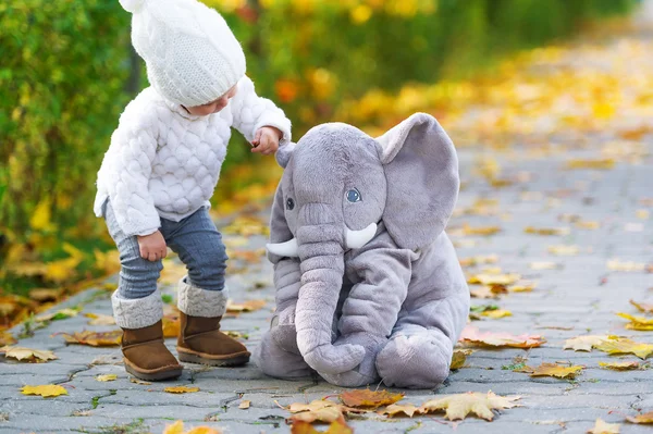 Девочка и игрушечный слон в осеннем городском парке . — стоковое фото